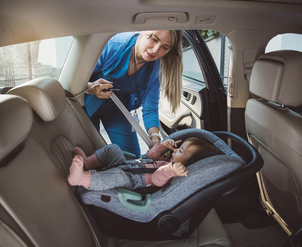 doctor who is also a mom getting her child fitted in a car seat