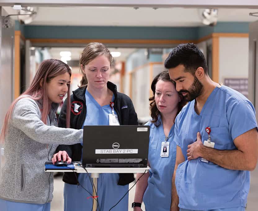 rounding team of four reviewing case details on the computer